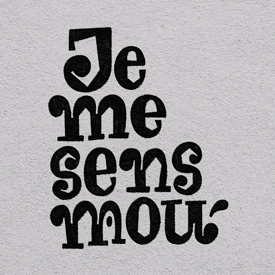 A lettering piece featuring the phrase 'Je me sens mou' ('I feel weak' in French) on black colour against a textured clear background. The letters are round in the outside and angular on the inside. The background looks like the rugged surface of a wall.